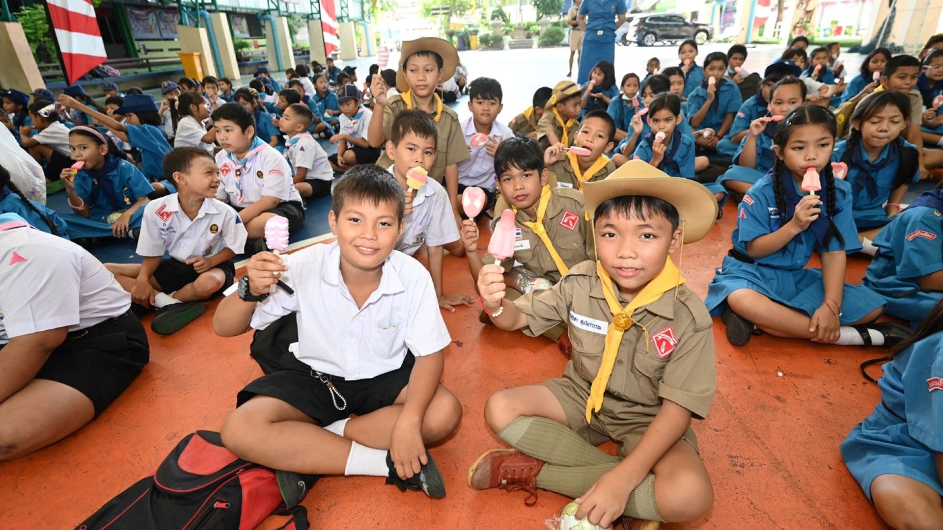 ภาพแสดงกลุ่มเด็กนักเรียนจำนวนมากถือไอสครีมวอลล์พร้อมรอยยิ้ม