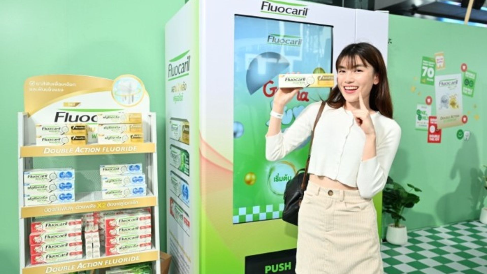 บูธโปรโมชั่นยาสีฟัน Fluocaril ที่มีผลิตภัณฑ์จัดแสดงอยู่หลายชนิด มีคนยืนอยู่หน้าบูธถือผลิตภัณฑ์