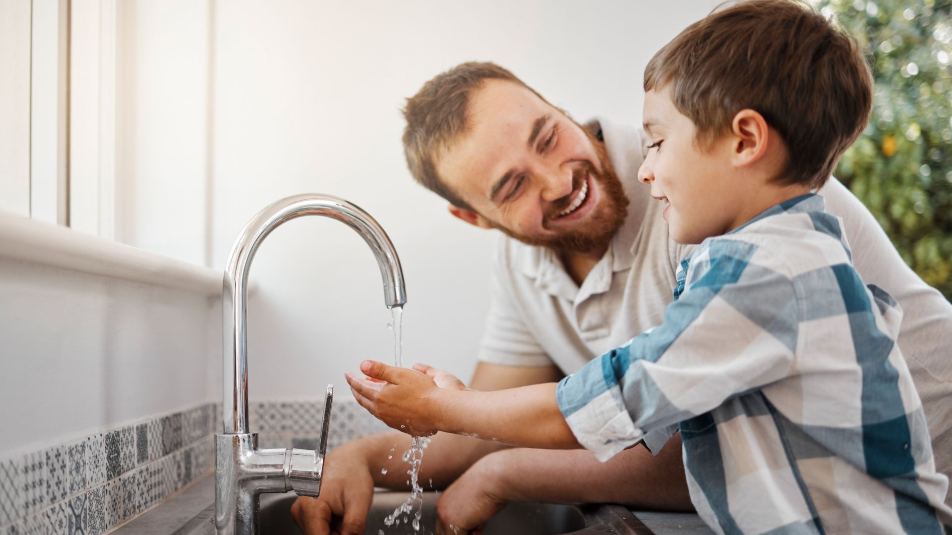 พ่อและลูกชายยิ้มแย้มขณะล้างมือที่อ่างล้างมือ