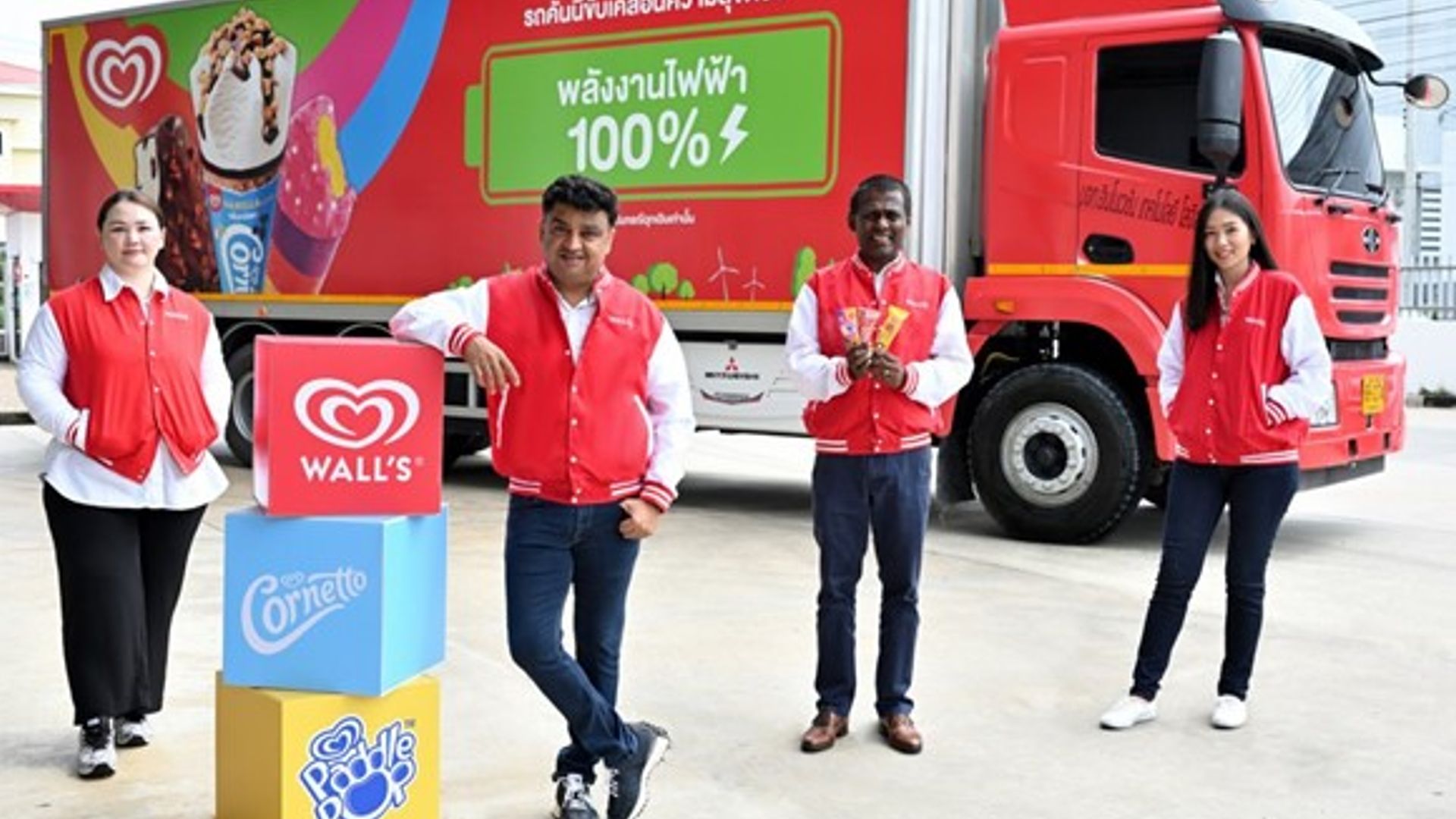 คนสี่คนอยู่ข้างรถไอศกรีมและกล่องที่มีโลโก้ Wall's, Cornetto และ Paddle Pop