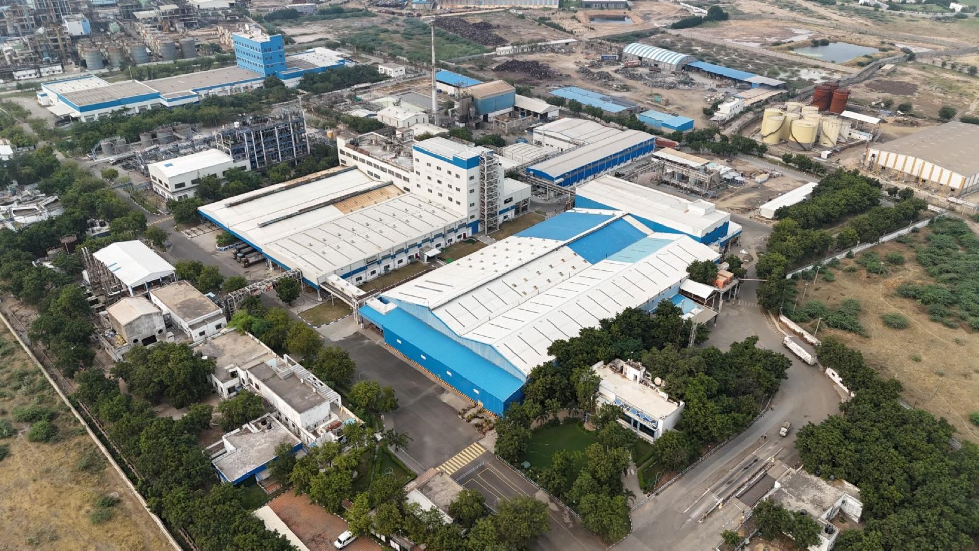 ภาพถ่ายมุมสูงของโรงงานคานธีธรรมของยูนิลีเวอร์ในประเทศอินเดีย ซึ่งเป็นโรงงานผลิตขนาดใหญ่ที่ตกแต่งเป็นสีขาวและน้ำเงิน