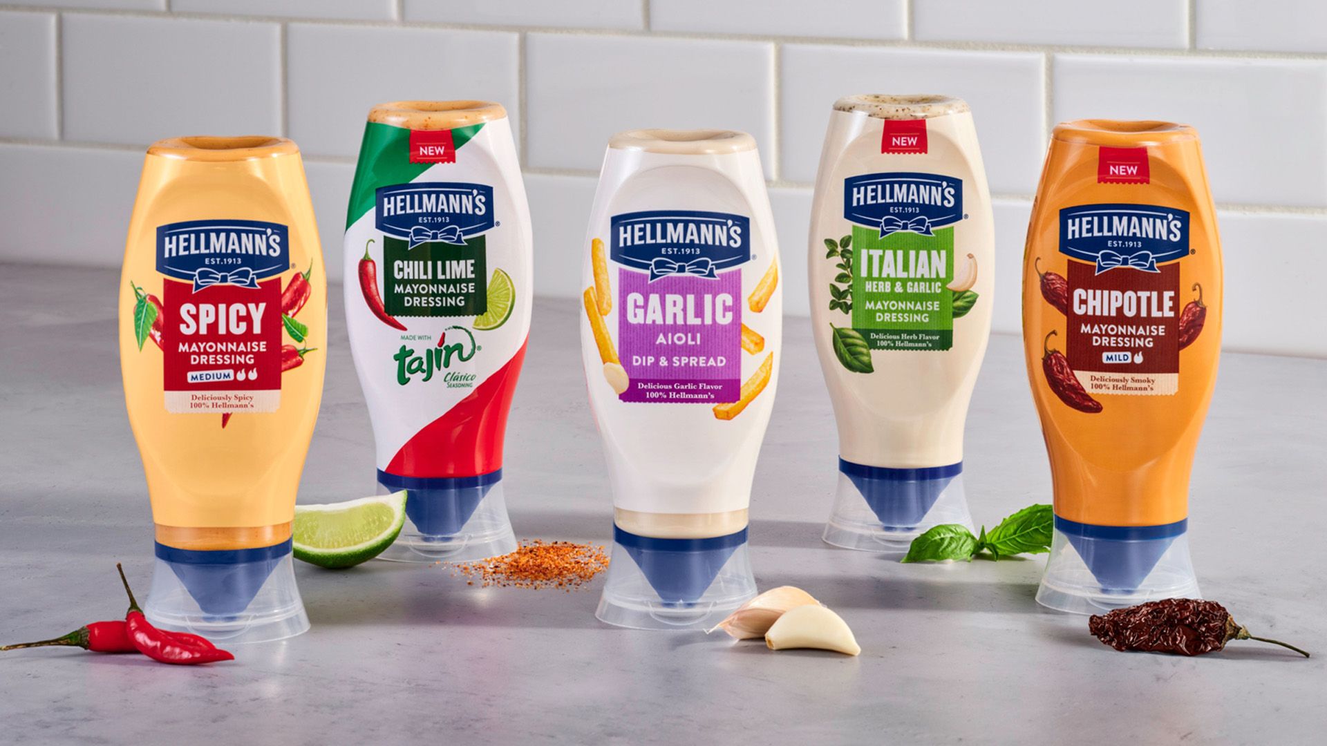 ภาพมายองเนสปรุงรสในขวดบีบของ Hellmann’s พร้อมส่วนผสมหลัก เช่น มะนาว พริก กระเทียม และสมุนไพร 